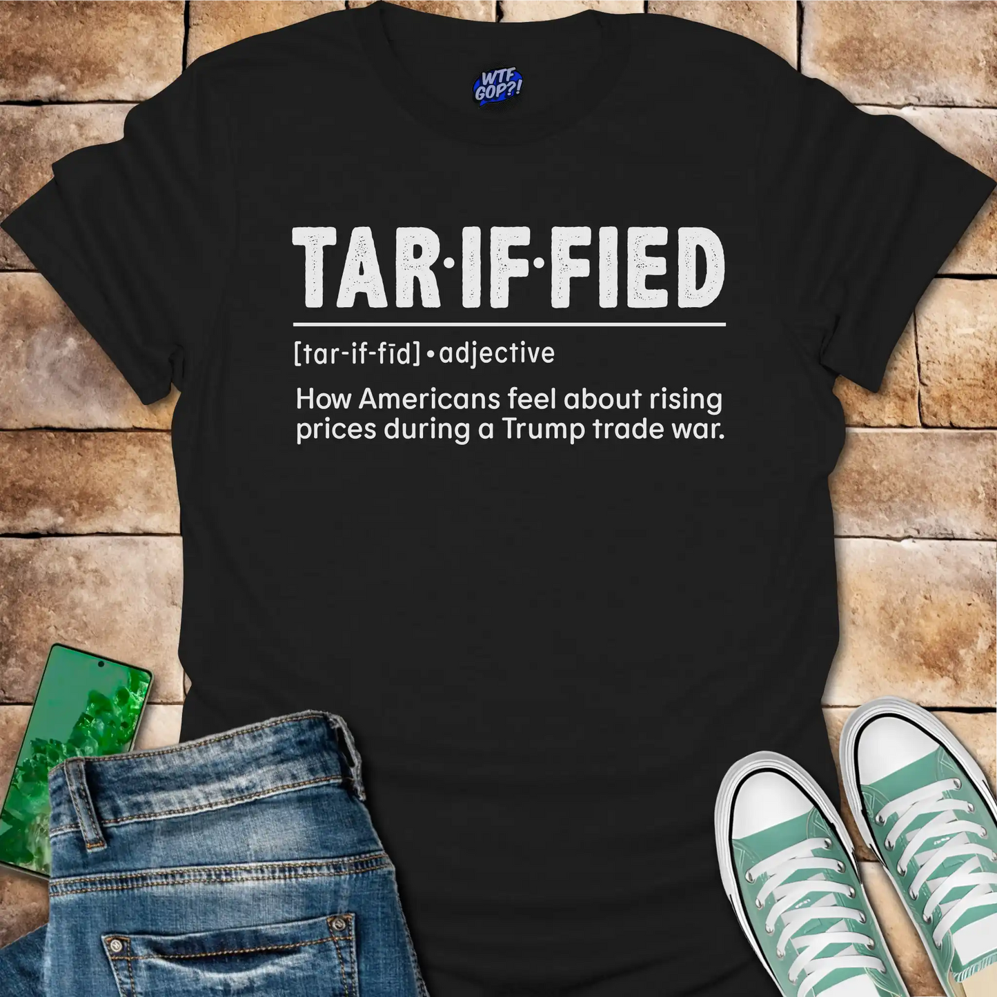 Black t-shirt with 'TAR-IF-FIED' text on a brick surface with jeans and sneakers.