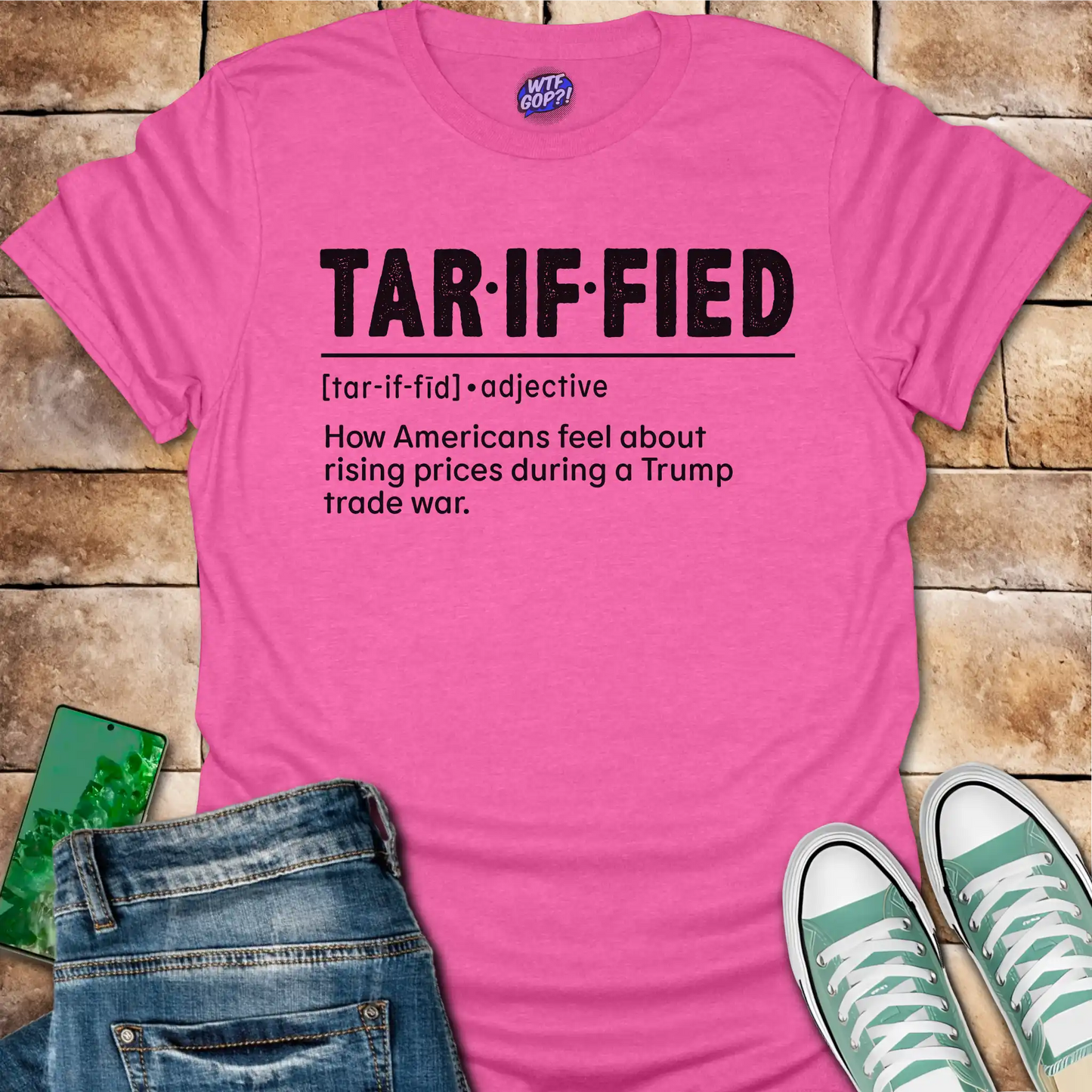Bright pink t-shirt with 'TAR-IF-FIED' text on a brick surface with jeans and sneakers.