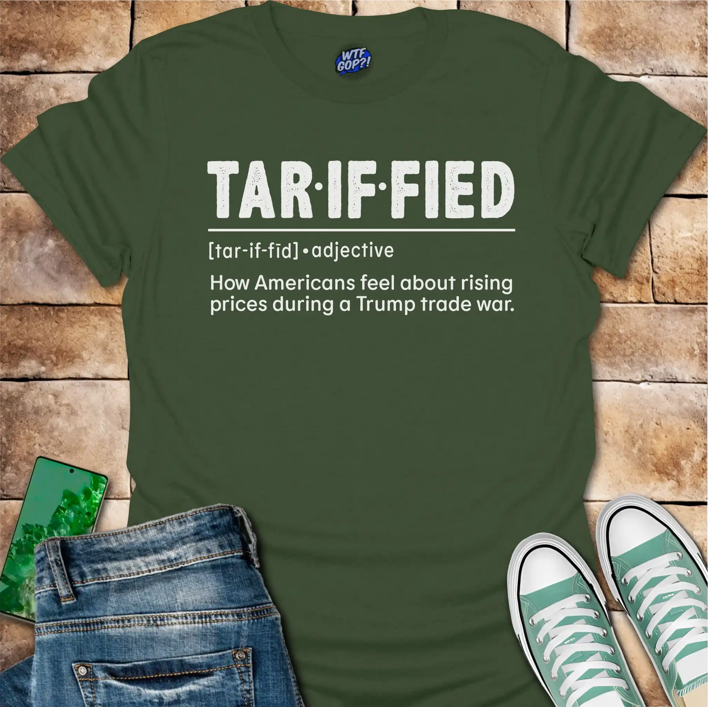 Military Green t-shirt with 'TAR-IF-FIED' text on a brick surface with jeans and sneakers.