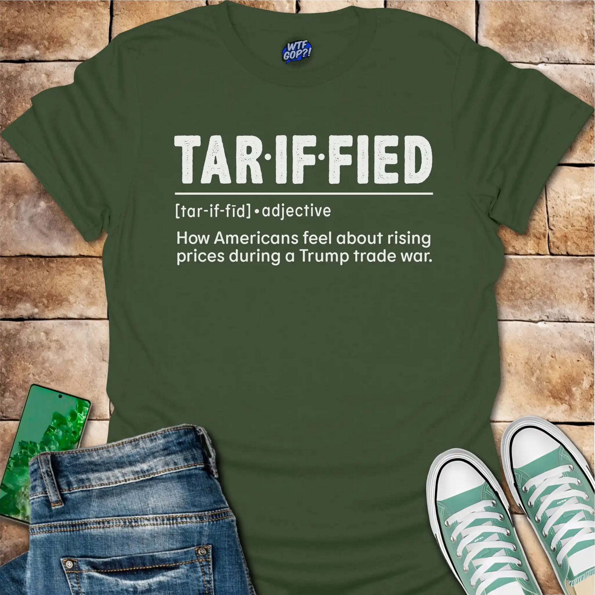 Military Green t-shirt with 'TAR-IF-FIED' text on a brick surface with jeans and sneakers.