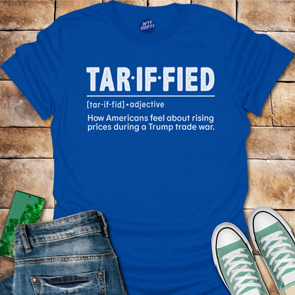 Royal blue t-shirt with 'TAR-IF-FIED' text on a wooden surface with jeans and sneakers.