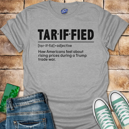 Gray t-shirt with 'TAR-IF-FIED' text on a wooden surface with jeans and sneakers.