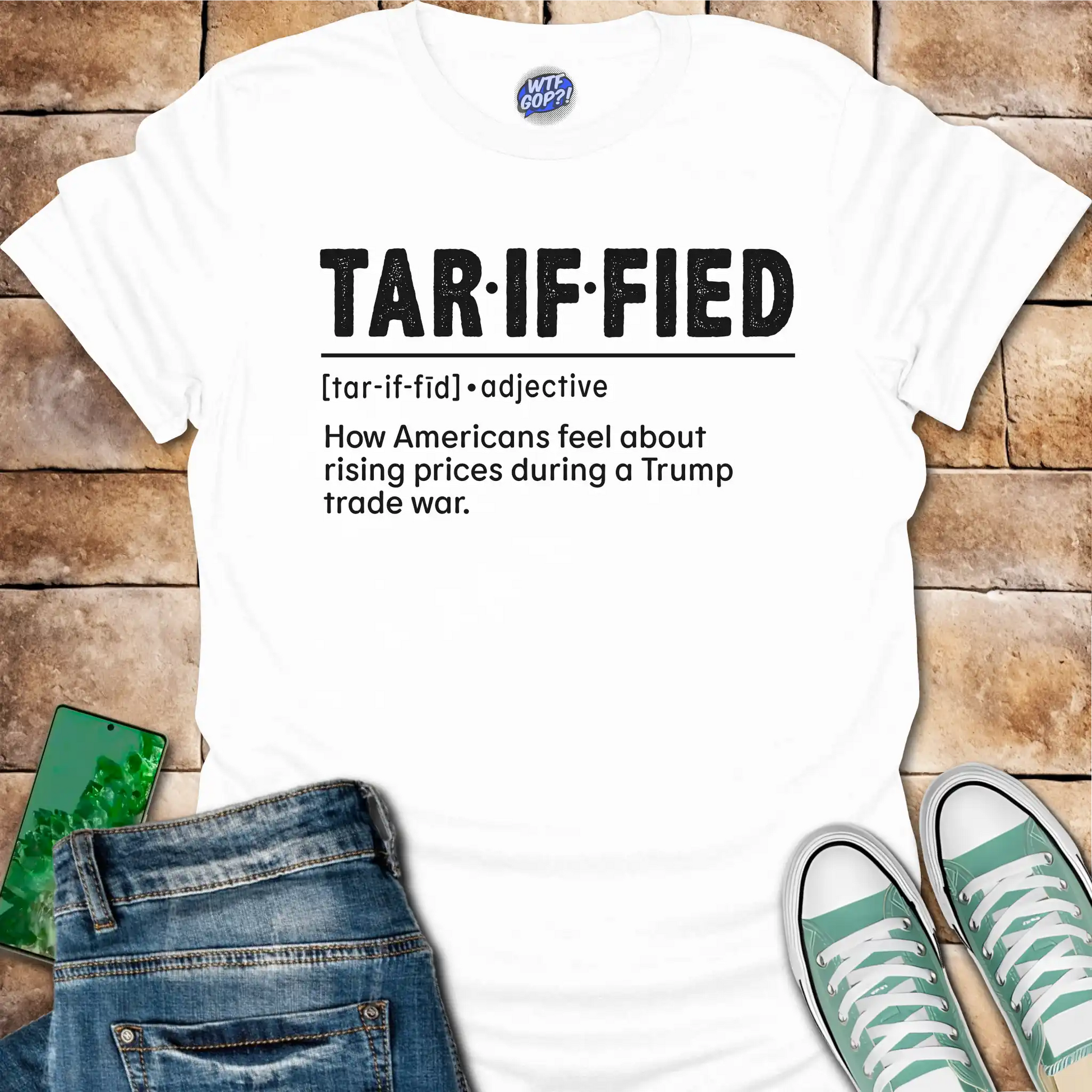 White t-shirt with 'TAR-IF-FIED' text on a wooden surface with jeans and shoes.